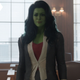 She-Hulk, wearing purple spandex under her gray business suit, smiles in a courtroom.